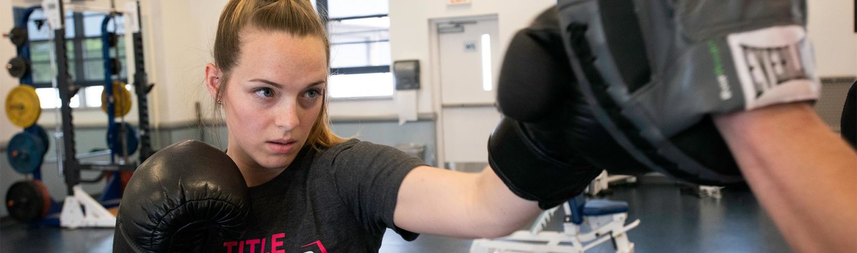 wellness-center-full-width Female boxer working with trainer.