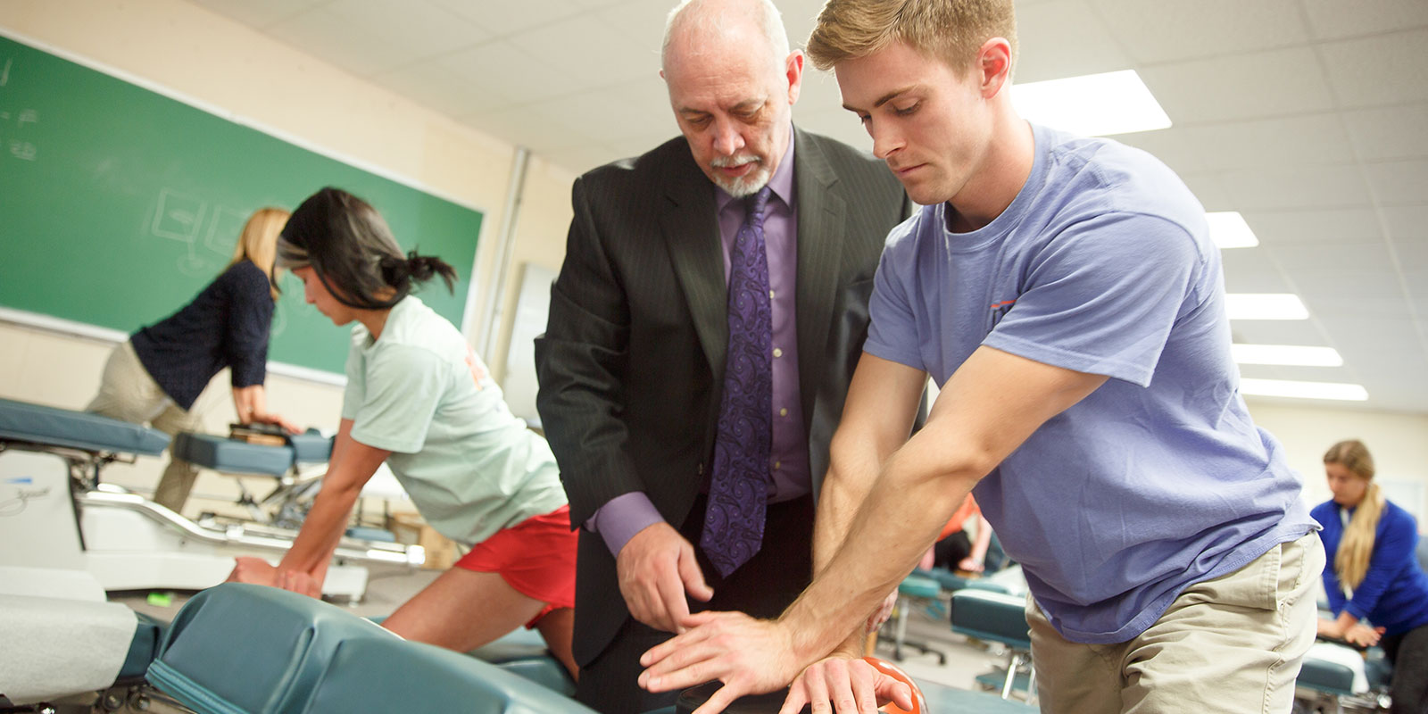 Student working with teacher on chiropractic technique.