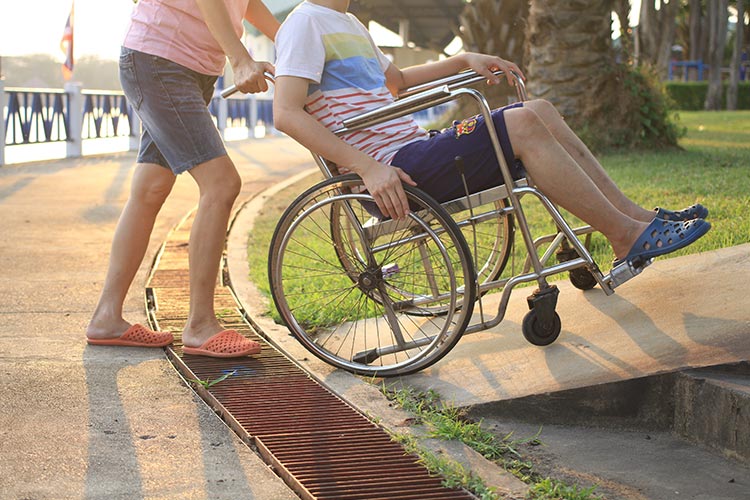 Woman helping male in wheelchair.