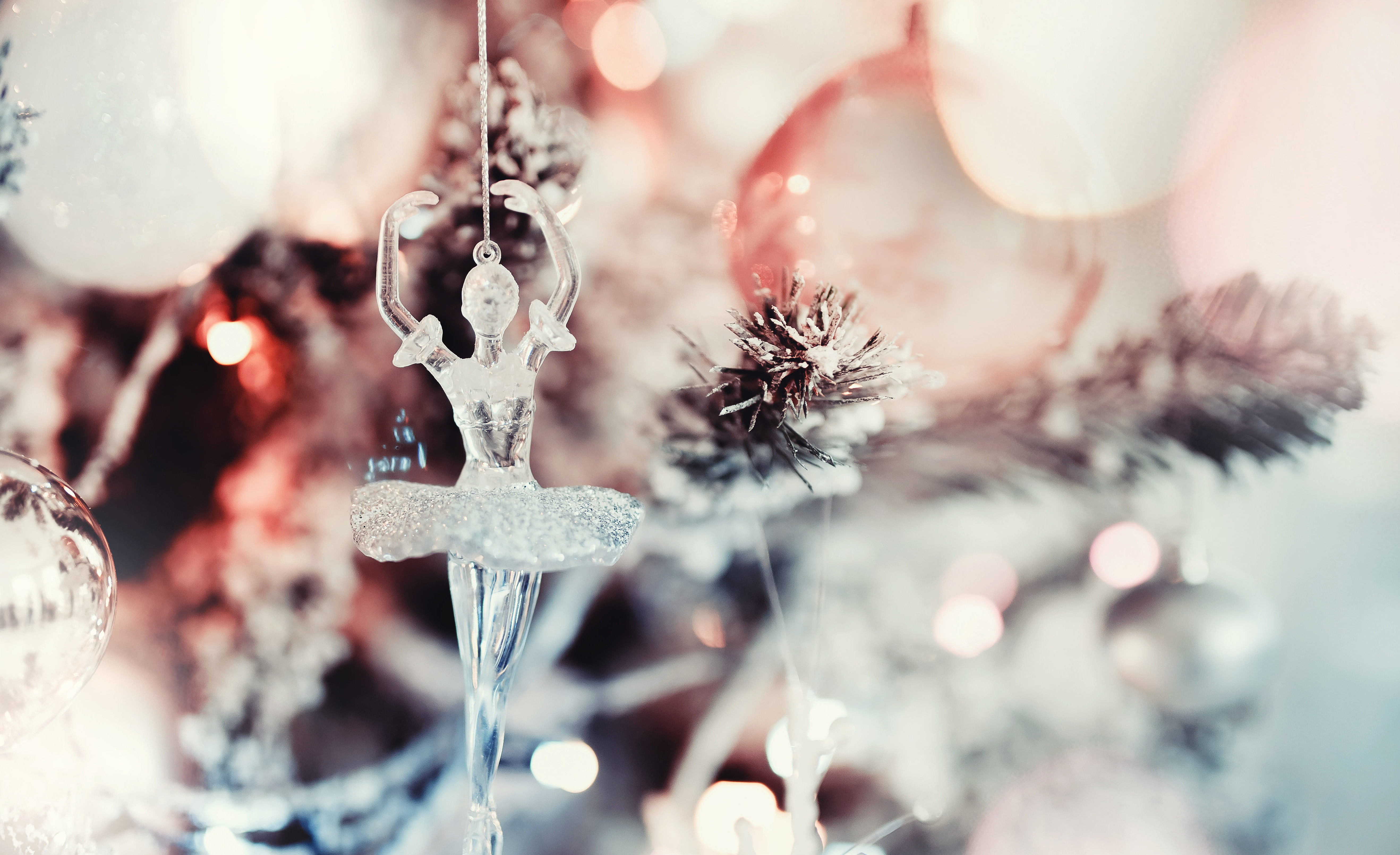 Glass ballerina ornament hanging on snow-dusted Christmas tree