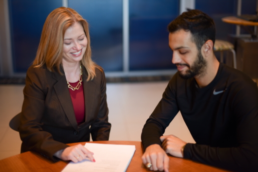 Dana Wehrli points to a piece of paper on a table as she meets with a student on campus