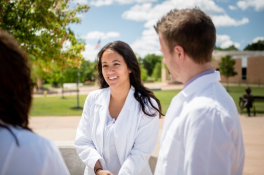 Three students stand in a circle talking on 威尼斯人app's campus